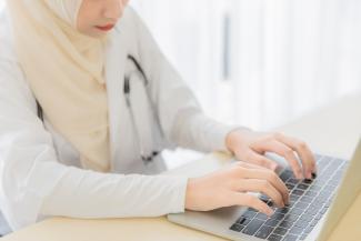 Muslim Nurse types on laptop